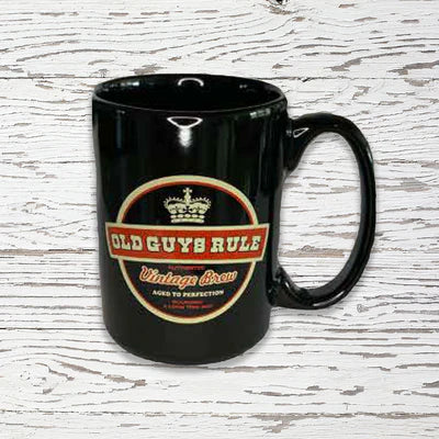 Black mug with 'Old Guys Rule' vintage beer design on a wooden surface