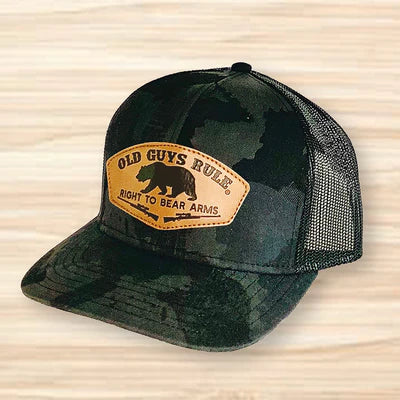 Green camouflage trucker hat with leather patch on a wooden surface